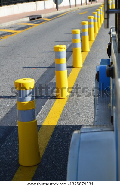 Yellow striped poles along the\
road divide the direction of traffic, the concept of road\
safety