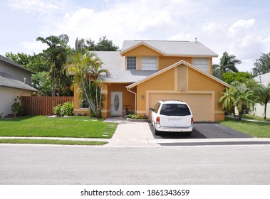 Yellow Suburban Back Snout Style Single Family Home With Parked Car In Driveway