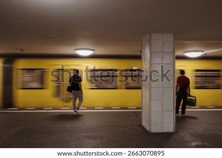 A yellow subway train creates a motion blur as it travels through a dimly lit U-Bahn station in Berlin, Germany. 