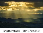 Yellow sun shafts through cloudy sky with long mountain range  and brighten foreest in Tak, Thailand