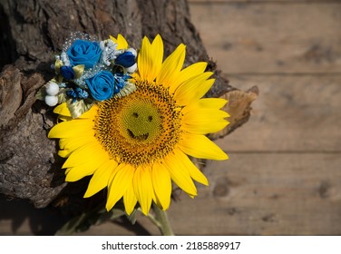 Yellow Sunflower With Carved Smile On It And Blue Flower Decoration. Symbolic Image Of Ukraine. Faith In Victory And Hope For Revival Of Country After Hostilities. Concept Of Positivity And Peace.