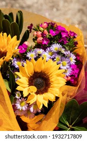 Yellow Sunflower And Purple Bouquet Of Flowers Wrapped In Tissue At A Florist.