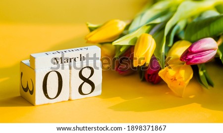 Yellow, sunny greeting card for Women's Day on March 8 with the number and month. Beautiful background of delicate tulips. March 8 and the concept of 
