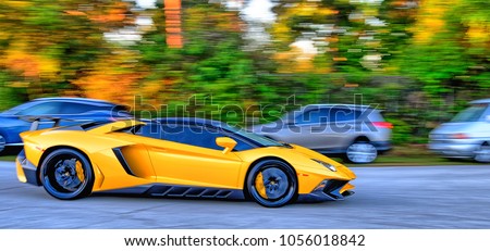 Yellow super car speeding down a road past other cars