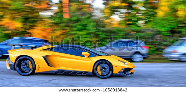 Yellow\
super car speeding down a road past other\
cars