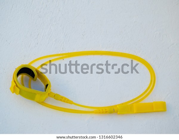 yellow surfboard leash on white concrete white\
floor. view from above.