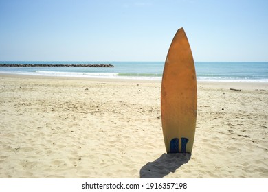 Yellow Surfboard In The Sand Beach With Horizontal Line Of Seascape In Background