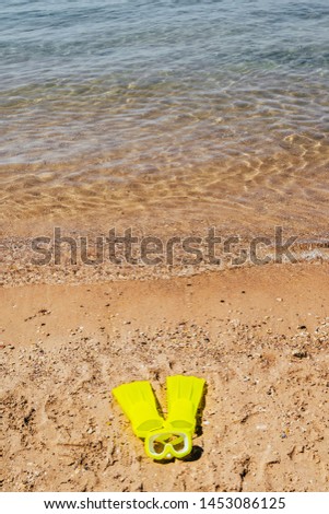 yellow swimming flippers and mask on sand beach by the sea