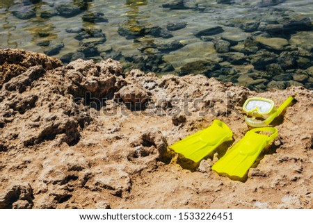 yellow swimming flippers with mask and tube on sand beach by the clear sea