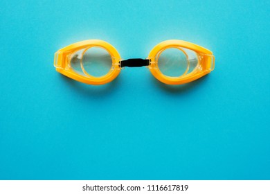 Yellow Swimming Goggles On Blue Background, Top View Flat Lay Minimal Composition