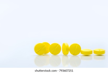 Yellow tablets pills on white background. Group of medicine. Prescription drug. Pharmaceutical industry. Health care and medicine concept. 7 round yellow tablets pills. Pharmacy drugstore banner.