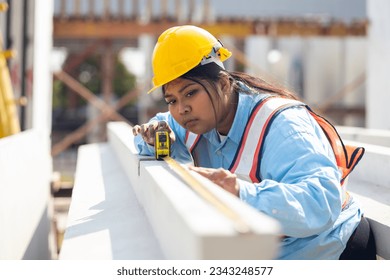 Yellow tape measure construction tools. Plus size female worker wearing safety hardhat inspec quality control at heavy Prefabricated concrete walls manufacturing factory - Powered by Shutterstock