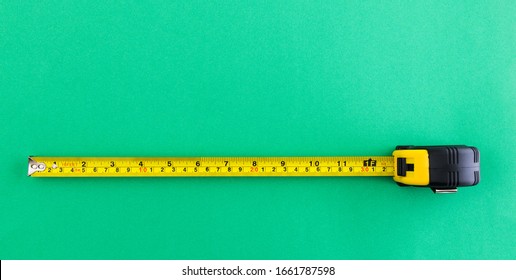 Yellow tape measure on green background.
