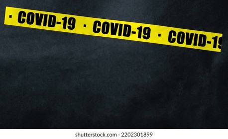 Yellow Tape With Text COVID-19 On A Dark Background. Warning Ribbon.