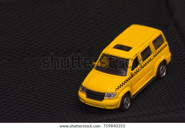 Yellow taxi car on black\
background. Children\'s toy car. Blurred background. Space for\
text.