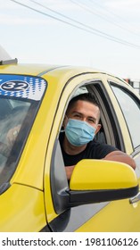 Yellow taxi. Latino taxi driver sitting with a mask for protection against the covid19 flu.