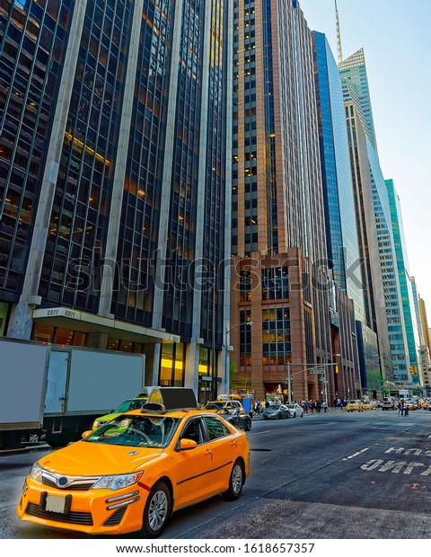 Yellow taxi on road. Street view in Financial\
District of Lower Manhattan, New York of USA. Cityscape with\
skyscrapers at United States of America, NYC, US. American\
architecture. Mixed\
media.