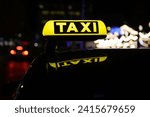 A yellow taxi sign illuminated by the daylight, mounted on the back of a vehicle, ready to provide transport services