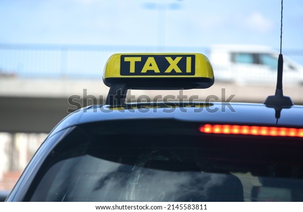 Yellow taxi sign on a black car in the city, detail\
of the vehicle for hire, copy space, selected focus, narrow depth\
of field