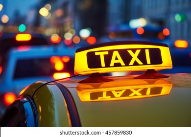 yellow taxi sign on cab car at evening or night in the city street