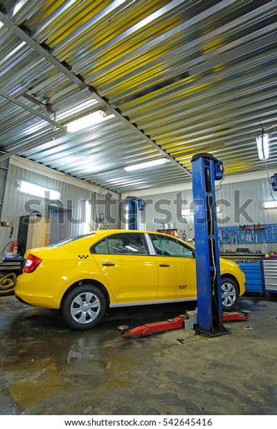 Yellow taxi\
under repair in a car repair\
station
