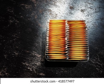 Yellow Tea Bags In A Plastic Box On Wooden Table.