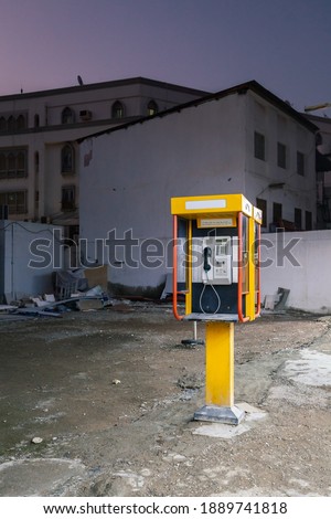 Yellow telephone booth in Muscat, Oman at dusk, no people