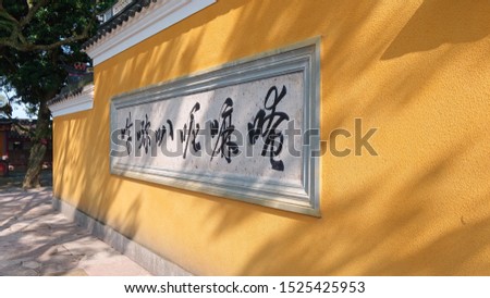 Yellow temple wall with mantra and sunny shadows, the six Chinese characters is the transliteration of Om mani padme hum.