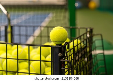 yellow tennis ball close-up on the edge of a black cart with tennis balls on the tennis court. - Powered by Shutterstock