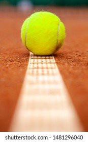 Yellow Tennis Ball Lies On The Clay Court Close Up.