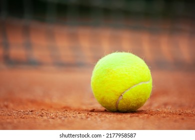 Yellow Tennis Ball Lies On The Clay Court Close Up.