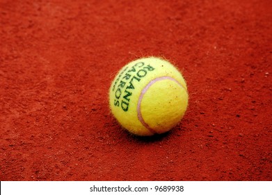 Yellow Tennis Ball Lies On The Red Clay Court Of Roland Garros, Paris