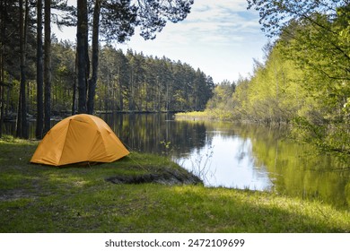 Yellow tent on the bank of a forest river. Spring trip to the national park. - Powered by Shutterstock