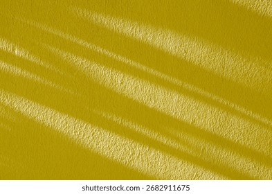 Yellow textured wall with dramatic diagonal shadows from natural sunlight, creating a minimalist and abstract background. Perfect for design, copy space, or artistic use