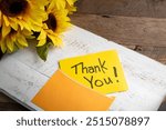 Yellow, Thank you note card with orange envelope, sunflowers and a wooden, white serving tray on a table.