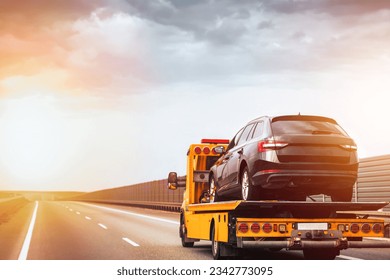 a yellow tow truck with a broken car on the highway road. Tow Truck Assisting Broken Down Vehicle on the Highway. Car service transportation and roadside assistance company concept.