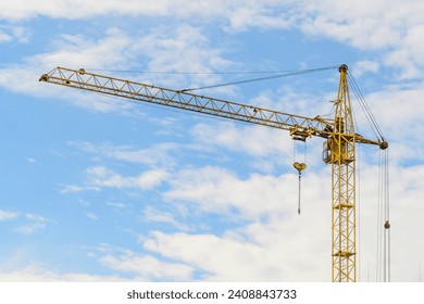 It is yellow tower crane  working in sunny day. There are clouds in blue sky. It is close up view.  It is midday time. - Powered by Shutterstock