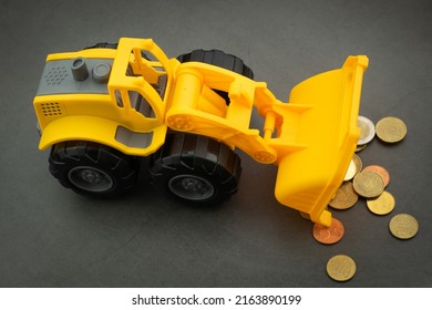 Yellow Toy Bulldozer, Excavator Carrying A Lot Of Money - Euro Cent Coins On Dark Background. Money Digging, Subsidies From European Union Concept.