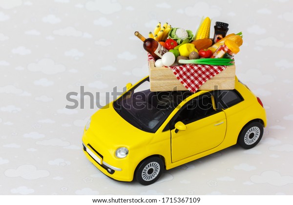 A yellow toy car delivering
food, drinks and grocery. Online food  shopping or donation
concept.