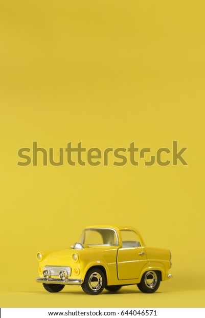 Yellow toy car on a\
yellow background.