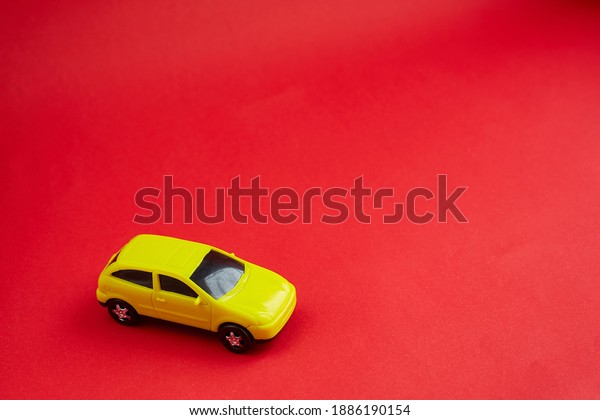 yellow toy car on red background,\
concept idea of taxi and cargo delivery during\
quarantine.