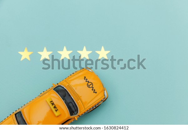 Yellow\
toy car Taxi Cab and 5 stars rating isolated on blue background.\
Smartphone application of taxi service for online searching calling\
and booking cab concept. Taxi symbol. Copy\
space