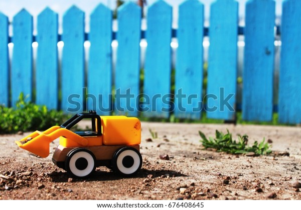 Yellow Toy Loader and Blue\
fence