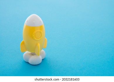 Yellow toy rocket flying launch with smoke on blue background copy space minimal style. Creative idea, inspiration, innovation, start up and growth education for successful concept.