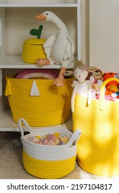 Yellow Toy Storage Baskets In The Children's Room. Cloth Stylish Baskets With Toys. Organizing And Storage Ideas In Nursery. Clean Up Toys And  Reduce The Clutter.