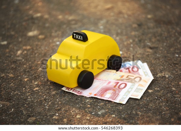 Yellow toy taxi with money\
on ground