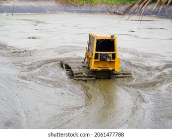 Yellow Tractor Cleaning The Drained Pond From Dirt And Debris.Remove Silt Ground