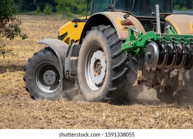 Yellow tractor with the cultivator turning around on the field - Shutterstock ID 1591338055