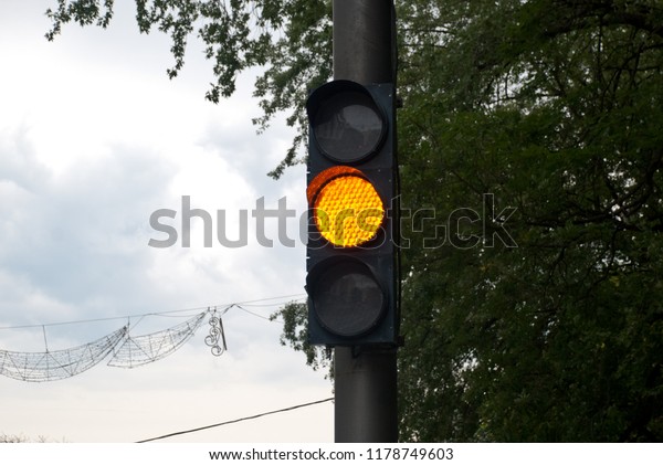 yellow\
traffic light (background: cloudy sky,\
trees)
