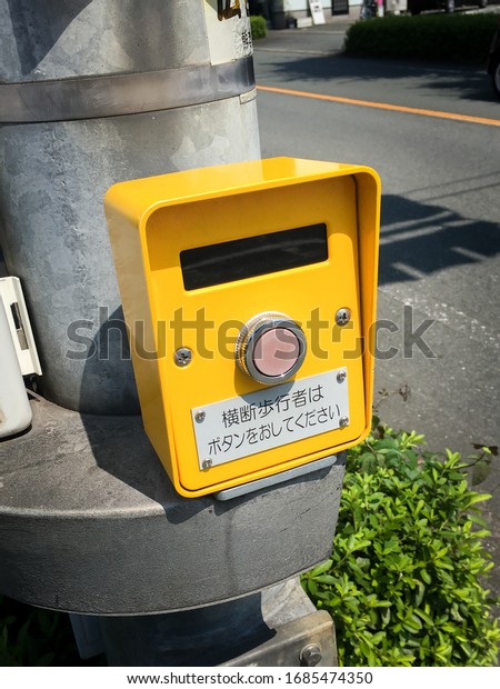 The yellow traffic\
light button which equipped on the pole on street for crosswalk,\
Kumamoto, Japan.\
Translation : Please push the button if you are\
crossing pedestrian.